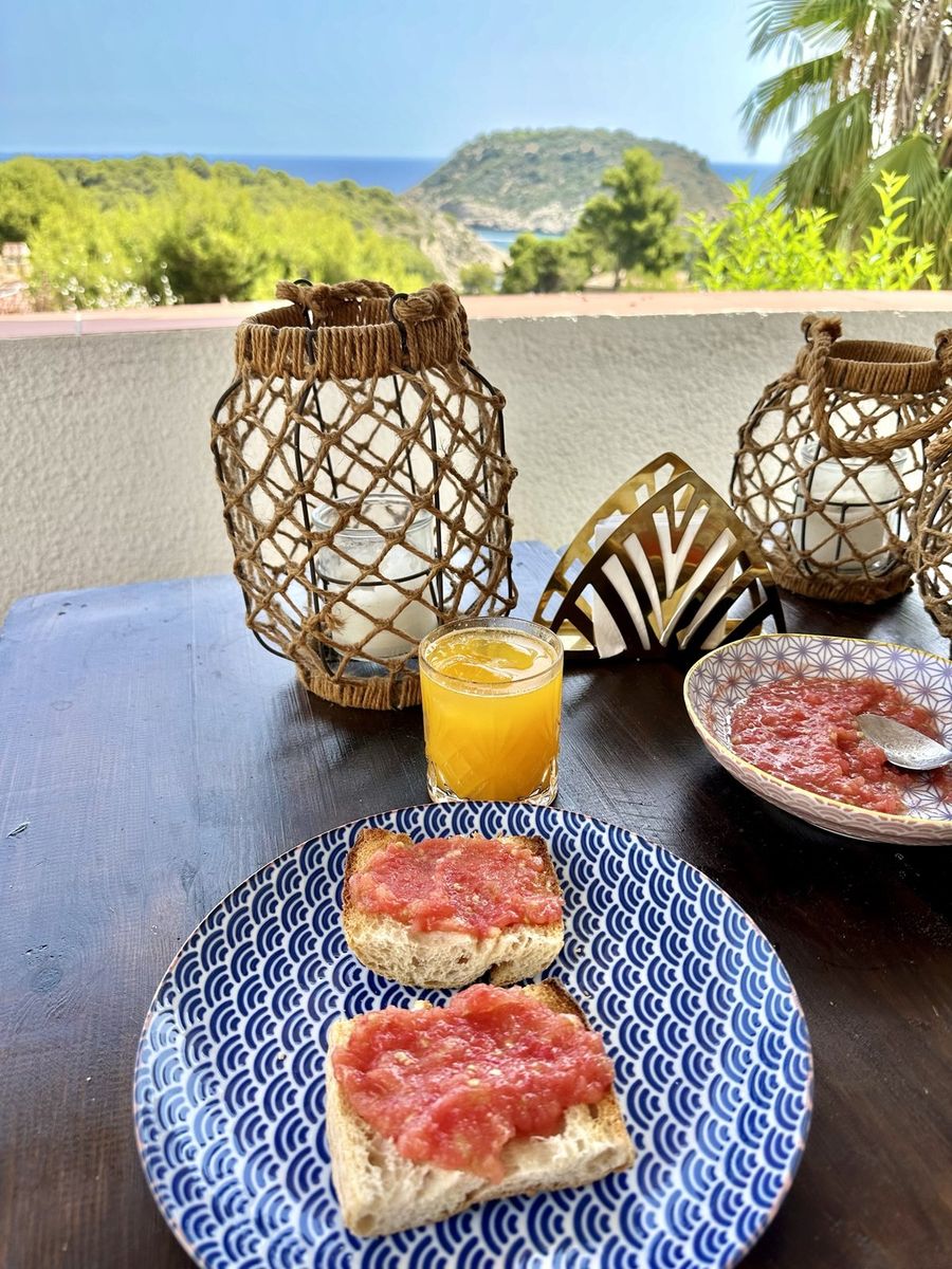 Petit-déjeuner de pain à la tomate et jus sur la terrasse, avec l'île au fond